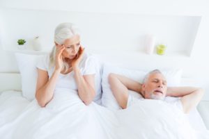 Woman holds her ears as her partner sleeps and snores sleep apnea dentist in Ardmore Pennsylvania